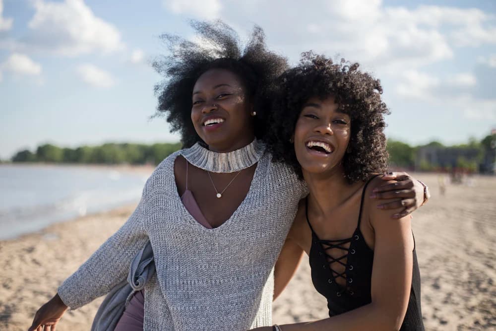 Two friends laughing together outdoors by the water